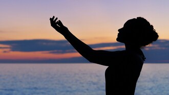A silhouette of a person gracefully raising their hands against the backdrop of a serene sunset by the sea reflecting the importance of balance and mindfulness in achieving overall fitness and well-being