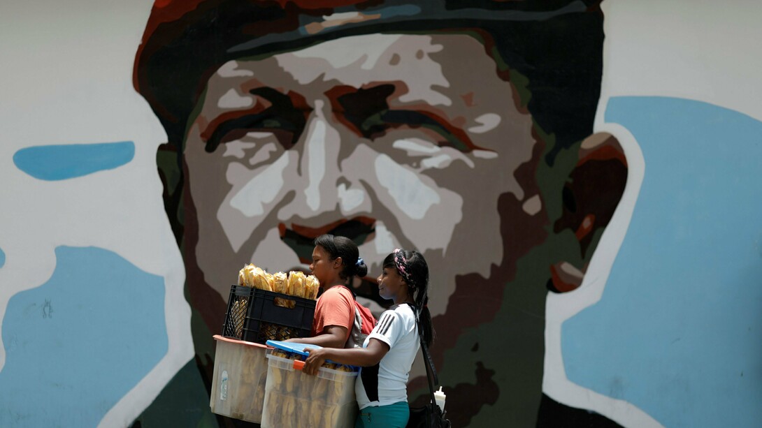 Dos jóvenes pasan delante de un mural que recuerda a Chávez en Caracas