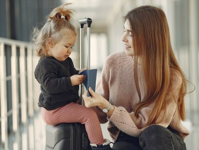 Mother and daughter waiting at the airport with a suitcase