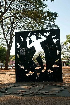 A obra escultórica do artista plástico goiano Siron Franco representa um tributo silencioso à vítima. A imagem reforça a ideia de que a memória coletiva resiste ao esquecimento institucional