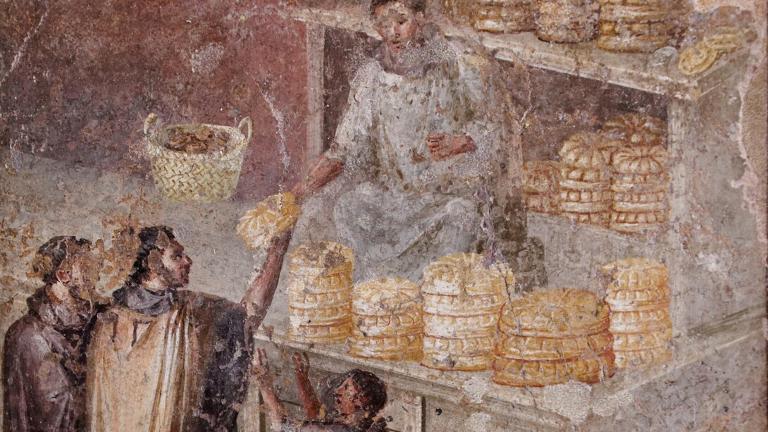Affresco comunemente interpretato come un "panettiere che vende il suo pane"; in realtà si tratta di una donazione di pane, probabilmente fatta per propaganda personale ed a fini politici; infatti l'uomo veste una toga, dunque non è un panettiere e men che mai una persona umile. Da Pompei, VII, 3, 30. MANN - Museo Archeologico Nazionale di Napoli, Italia