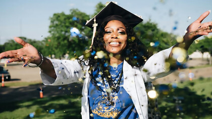 Celebrating her university graduation with exuberance, an African American woman joyfully throws confetti, marking the culmination of her academic journey and the beginning of a new chapter in her life