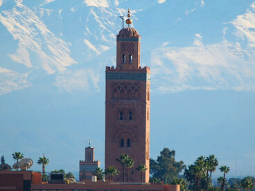 Le minaret s’élève dans la lumière du soir, avec les montagnes de l’Atlas comme arrière-pays éternel de la ville de Marrakech au Maroc