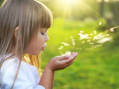 Una niña soplándole a una flor