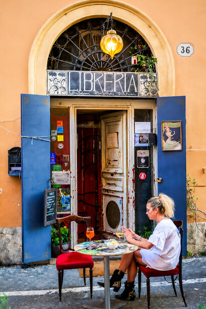 A young woman enjoying the atmosphere of a trendy bookstore in an alleyway in the heart of Rome’s Rione Monti district, Italy