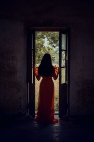 Standing at the threshold between darkness and light, she pauses in the stillness of becoming