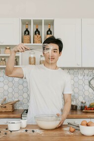 A man holds a whisk over a bowl of pancake mix, working as a chef