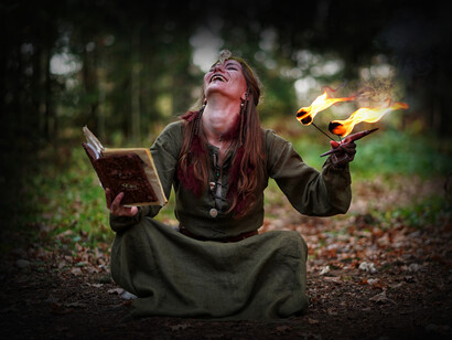 Mujer ríe mientras coge un libro de 'magia' disfrazada de hechicera