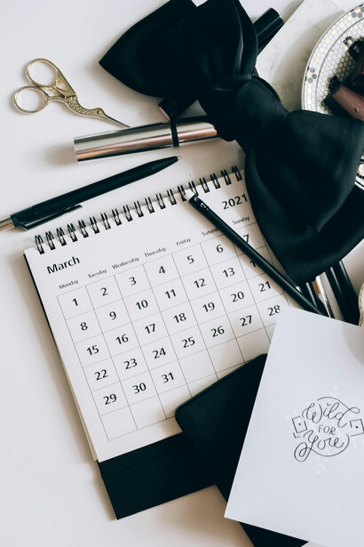 A calendar, coffee, and chocolates are placed on a white table