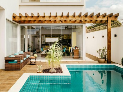 A sunlit pool terrace framed by sliding glass walls, representing the effortless integration of leisure and living spaces