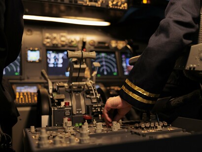 A pilot adjusting aircraft controls in the cockpit, symbolizing human oversight and the importance of retaining control as machines take on increasingly complex task