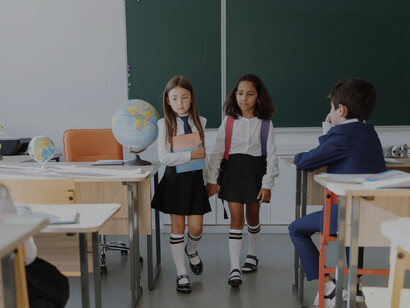 Dos amigas de la escuela yendo a sus lugares en la clase juntas, vestidas con los uniformes escolares