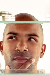 A man thinking about which product to pick up for his daily self-care routine