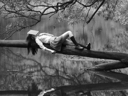 Falling asleep reading, a woman dreams on tree branch on the river