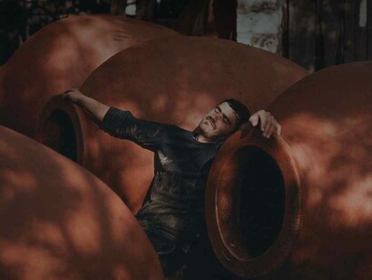 A euphoric man in total bliss among the giant Qvervis as he's resting his hands on their rims after perhaps having too much to drink