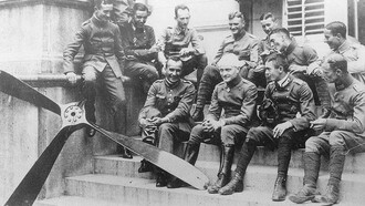 The Red Baron with his bandage seating with his flying circus in the summer of 1917, Carlos in the back row lighting a cigar