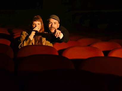 A couple sitting in a movie theater, absorbed in the shared stillness of the screening