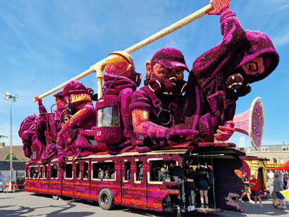 La parte inferior de la carroza muestra el metro, en el que se encuentra un numeroso grupo de figurantes vestidos con atuendos similares a los de las figuras de la carroza. Carroza titulada "Distopía", desfile de flores, 2023. Aldea de Klein Zundert, Holanda