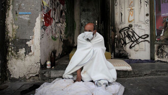 Una persona sin hogar descansa en el portal de un edificio abandonado, España