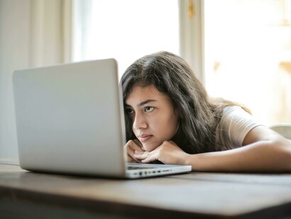 A young woman using her laptop at home, showing signs of digital anxiety, information overload, and news-scrolling stress