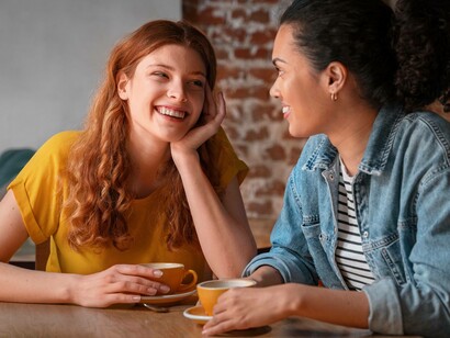 Due persone che ridono al tavolino di un bar: "Sin dalla nostra comparsa sulla Terra, e per tutto il nostro lungo percorso evolutivo, abbiamo sviluppato un linguaggio — prima attraverso i gesti, poi con la voce e infine anche con la scrittura — che potesse essere condiviso unicamente con altri esseri umani..."