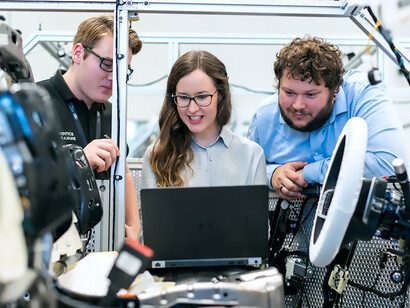 Three engineers collaboratively immersed in their tasks within the workshop, seamlessly coordinating their efforts to navigate through the intricate machinery and contribute to the collective productivity of the workspace