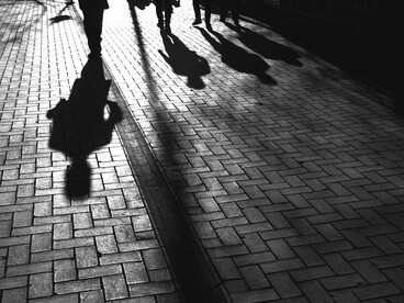 Silhouetted figures walk down the sidewalk at dusk