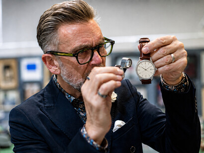 Watch dealer inspecting an antique clock before an auction