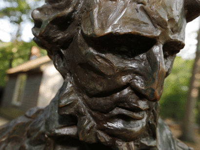 Estatua de Thoreau en Walden Pond: detrás se vislumbra la réplica de la cabaña