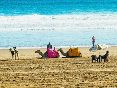 Camelo e pessoas em praia de Agadir, em Marrocos. Estávamos em casa, mesmo a milhares de quilômetros de distância