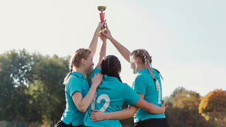 Girls celebrating with raised trophies at an awards ceremony, showcasing community recognition and public appreciation events