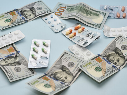 A pile of pills and money placed on a table, symbolizing the intersection of medicine and wealth