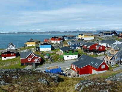Casas coloridas se espalham pelo terreno rochoso de Nuuk diante das águas costeiras da Groenlândia. A ocupação humana aparece integrada a uma paisagem marcada pelo isolamento e pelas condições naturais do extremo norte