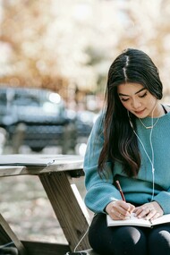 Adolescente con le cuffie scrive sul diario. Il viaggio della lettura: una ragazza tra le pagine e le strade affollate della vita