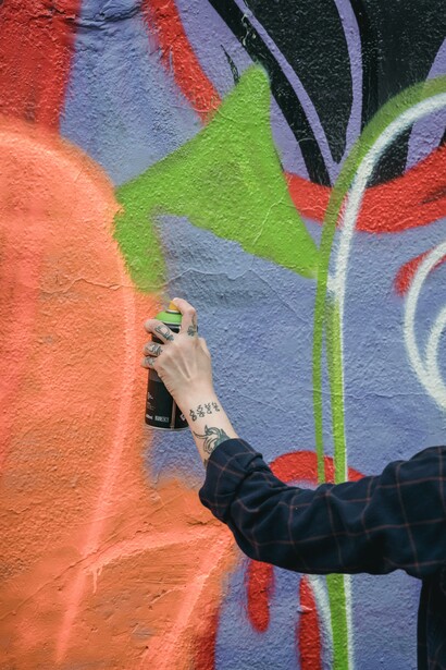 Person creating graffiti art on a wall