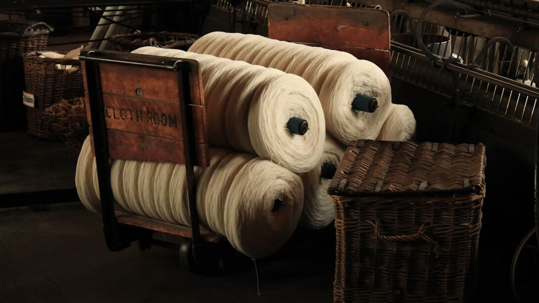Several rolls of yarn made from plant-based fibers resting on a wooden cart, showcasing natural materials used in sustainable fashion