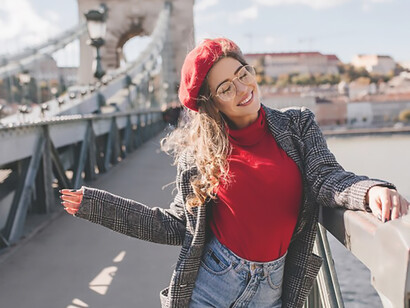 A fashionable solo female tourist, casually attired, relishes the delights of urban exploration, exuding a contagious blend of fun and independence