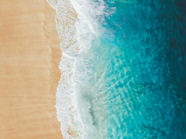 A água cristalina encontra a faixa de areia em uma composição marcada por diferentes tons de azul e dourado. Diante de paisagens assim, a viagem deixa de ser apenas deslocamento e passa a ser uma experiência de descoberta interior