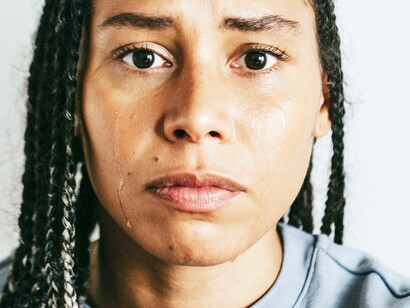 A woman expressing sentiment over a loss by shedding a tear