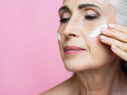 An older women applying anti aging cream to smooth over the evidence of age 