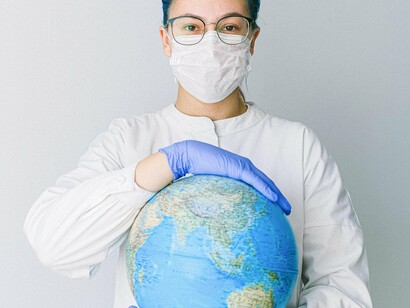 Mulher segura globo terrestre com máscara e luvas de proteção. Além dos efeitos das vacinas, a própria Covid-19 gerou um novo problema de saúde global: a "Covid Longa" ou síndrome pós-Covid. Milhões de pessoas relataram sintomas persistentes meses após a infecção, incluindo fadiga crônica, confusão mental e problemas cardiovasculares  



