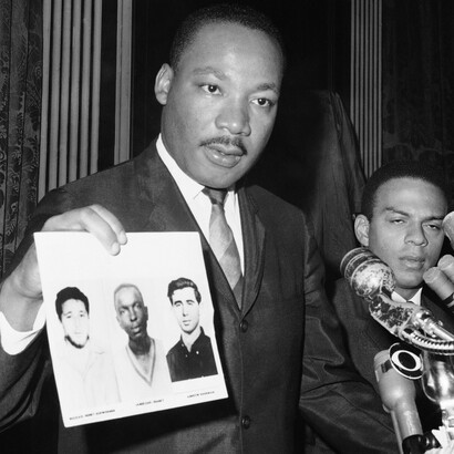 Martin Luther King displays pictures of three civil rights workers murdered, Cheney, Goodman and Schwarmer