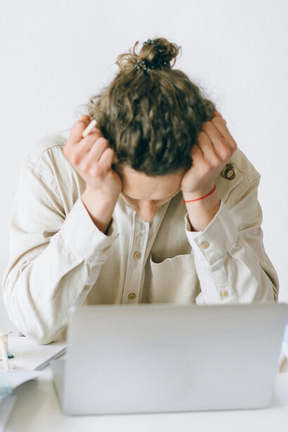 A man in a white shirt sits at a table working, visibly burned out