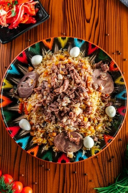 A colorful plate of plov sits on a wooden table, highlighting one of Uzbekistan’s most popular and beloved dishes