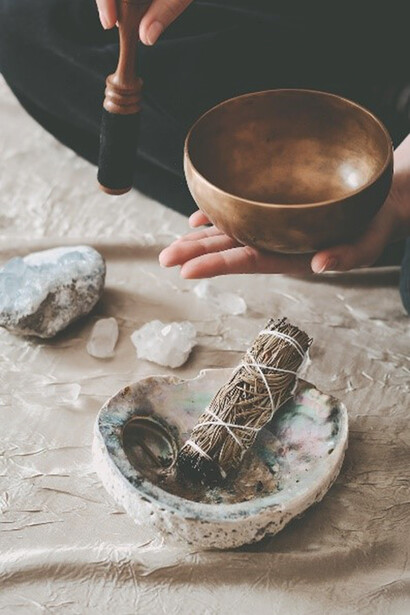 A girl delicately cradles a shimmering gold Tibetan bowl, immersing herself in the holistic sounds it emits
