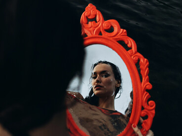 A woman in a bathing suit gazing at her reflection on the surface of the sea