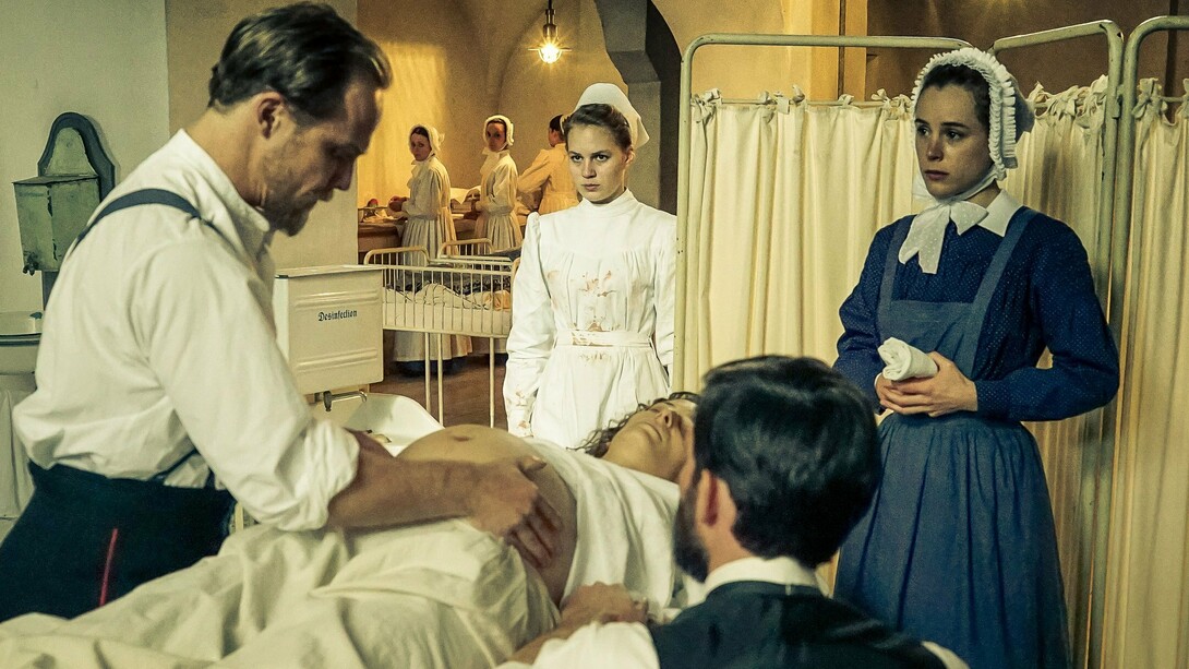 «Charité» es una serie alemana de TV que se ha convertido en uno de los grandes fenómenos audiovisuales de los últimos años. La acción se desarrolla en el famoso hospital berlinés en la segunda mitad del siglo XIX para narrar las peripecias de algunos de los facultativos más importantes de la historia (todos ellos han han sido tratados aquí bajo la pluma magistral del autor de este artículo, Ronald Evans). En la imagen, Emil Behring (Matthias Koeberlin, izquierda) examina a la esposa embarazada Paul Ehrlich (Christoph Bach, sentado, de espaldas)