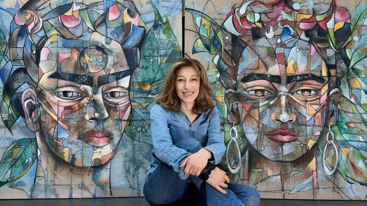 Frédérique Assaël frente a dos de sus retratos de Frida Kahlo