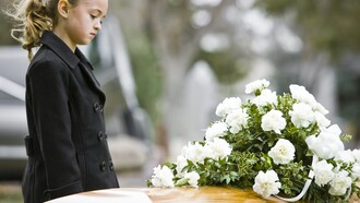 Una niña junto a un ataud