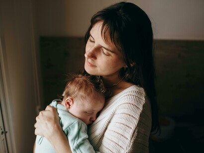 A woman holding a baby in her arms by the window